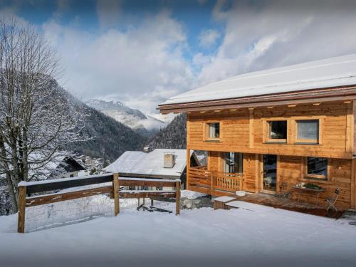 une cabane en rondins dans la neige avec des montagnes en arrière-plan dans l'établissement Chalet Limanosa - OVO Network, à La Clusaz