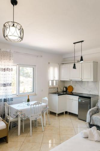 a kitchen with white cabinets and a table in a room at Mariana Apartments in Sarandë