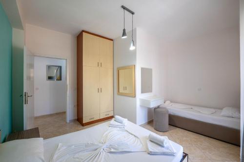 a white bedroom with two beds and a closet at Mariana Apartments in Sarandë