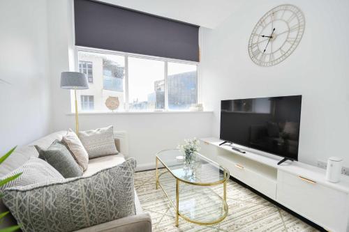 a living room with a couch and a tv and a clock at Compact & Convenient 1 Bed Apartment in Bradford in Bradford