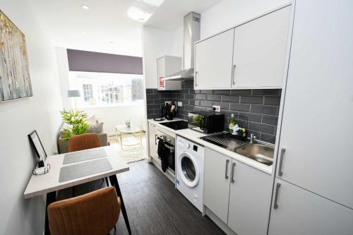 a kitchen with white cabinets and a sink and a dishwasher at Compact & Convenient 1 Bed Apartment in Bradford in Bradford