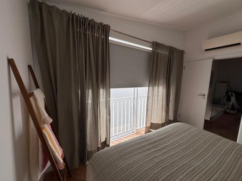 a bedroom with a bed and a large window at Stylish townhouse with gallery in the heart of Tavira for two in Tavira