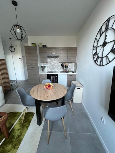 une salle à manger avec une table, des chaises et une horloge dans l'établissement Le Clair & Confort, au Mans