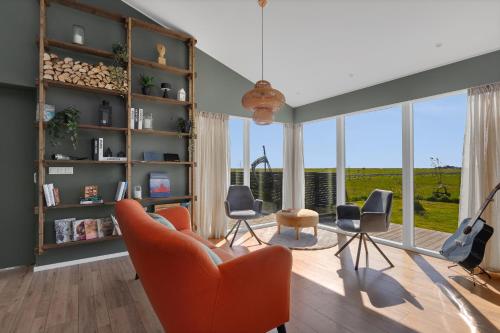 a living room with orange chairs and a large window at Mói Byggðarhorn in Selfoss