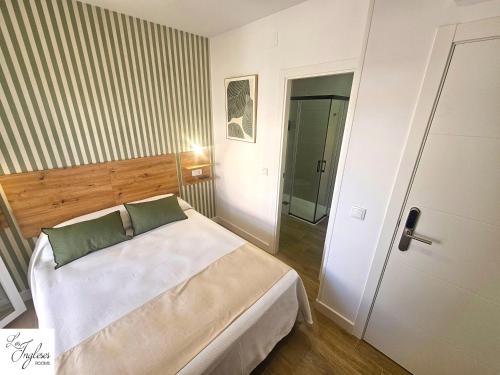 a bedroom with a white bed and a door at Los ingleses rooms in Punta Umbría
