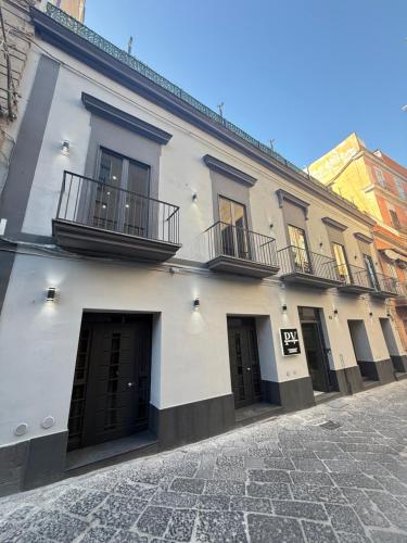 a white building with black doors and balconies on a street at Palazzo Valentino in Naples
