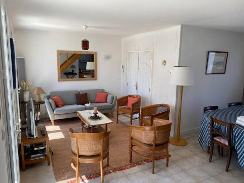 a living room with a couch and a table and chairs at La Villa de la Digue in Saint-Clément-des-Baleines