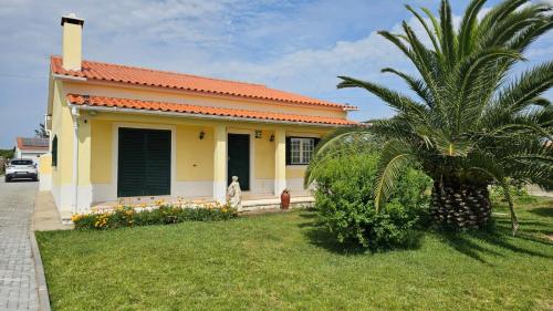 a small yellow house with a palm tree in the yard at Quinta Marinhais Privada no Ribatejo com Piscina, BBQ e Animais, Perto de Lisboa in Marinhais