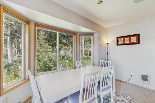 a dining room with a white table and chairs and windows at Snug Harbor Hideout in Islandale