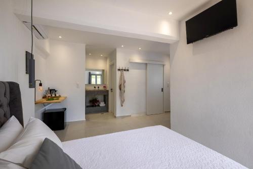 a bedroom with a white bed with a television on the wall at Chrysonisos Suites with Sunset & Seaviews near Kini in Ano Syros