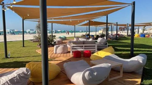 eine Gruppe weißer und gelber Sitzsäcke unter einem Regenschirm in der Unterkunft Villa 4 bedrooms, Sedra resort, North coast in Sidi Kirayr