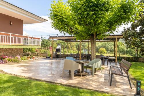 a patio with tables and chairs under a tree at Can Pons De Dalt Casa rural a la Selva in Girona