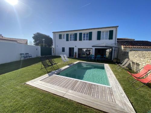 a backyard with a swimming pool and a house at La Villa des Lauriers in La Flotte