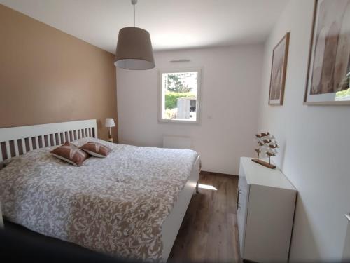 a white bedroom with a bed and a window at Le petit logis de Barneville plage in Barneville-Carteret
