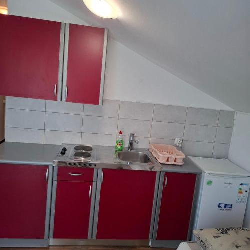 a small kitchen with red cabinets and a sink at nnnnn in Bilice