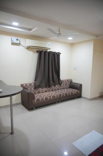 a couch sitting in a room with a curtain at Hotel Udyam Glory in Nagpur