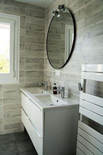 une salle de bain avec un lavabo blanc et un miroir dans l'établissement Les Magnolias à 5 minutes du Lac du Der, à Ambrières