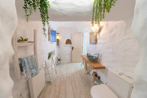 a small white room with a toilet and a table at Complejo Cuevas Otto in Baza