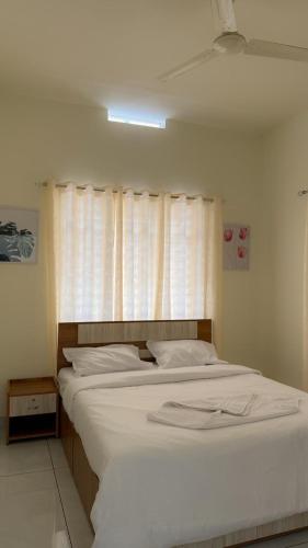 a bedroom with a large white bed with a window at MIDDLE WAYANAD HOLYDAY Inn in Kaniyāmbetta