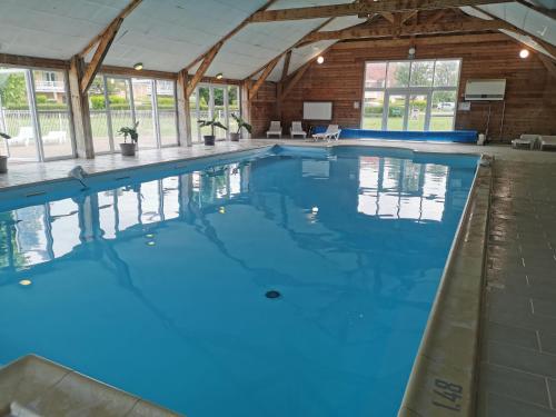 une grande piscine intérieure d'eau bleue dans l'établissement Les Portes d'honfleur, à Boulleville