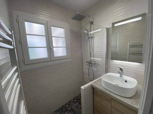 a white bathroom with a sink and a shower at La maison de la Sauzaie in La Flotte
