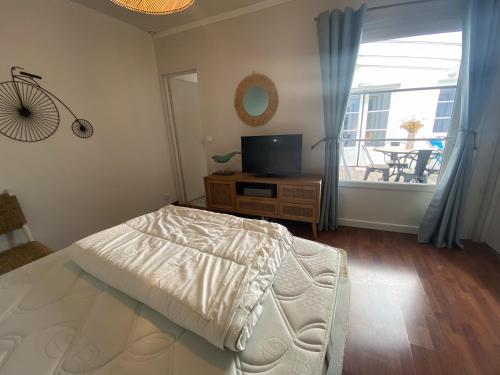 a bedroom with a bed and a television and a balcony at La maison de la Sauzaie in La Flotte