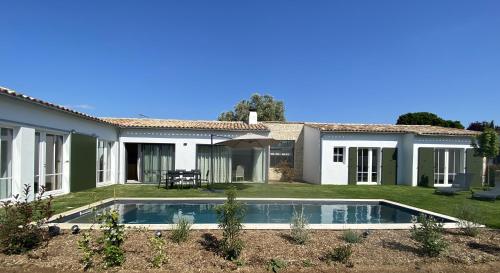 une maison avec une piscine dans la cour dans l'établissement La Villa Mirabelle, à Loix