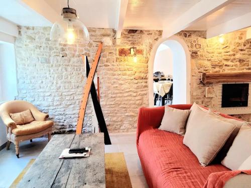 a living room with a red couch and a stone wall at La Maison du Puits Fleuri in Ars-en-Ré