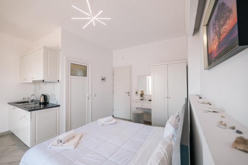 a white room with a bed and a kitchen at Mariana Apartments in Sarandë