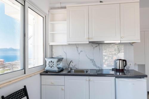 a kitchen with white cabinets and a sink and a window at Mariana Apartments in Sarandë