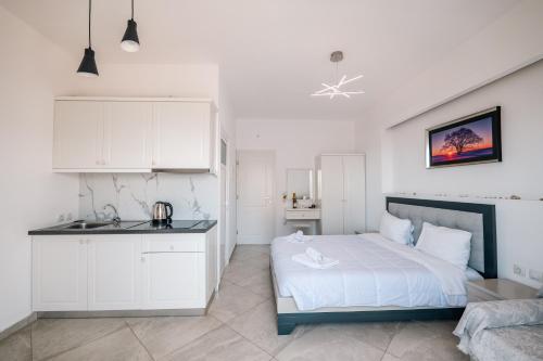 a white bedroom with a bed and a kitchen at Mariana Apartments in Sarandë