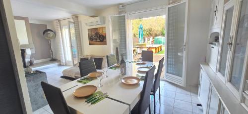 une cuisine et une salle à manger avec une table et des chaises dans l'établissement Villa Mauricette, clim piscine, à Sérignan