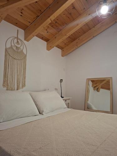 a bedroom with a bed with a mirror and wooden ceilings at Beautiful Plomari Cottage in Plomari