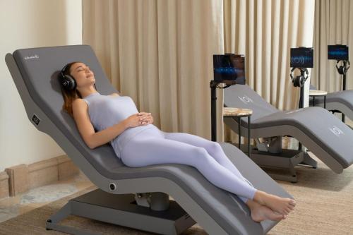 a woman laying in a chair with headphones at Fairmont Grand Del Mar in San Diego