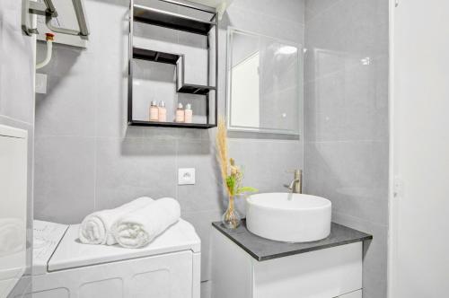 une salle de bain blanche avec un lavabo et un miroir dans l'établissement Suite Maxime Chauchat - Paris Opéra, à Paris