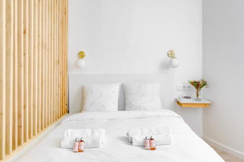 - une chambre avec un lit blanc et 2 bouteilles dans l'établissement Suite Maxime Chauchat - Paris Opéra, à Paris