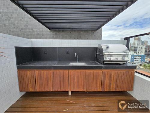 una cucina con lavandino e griglia sul balcone di Get by Side Suites a Tambaú