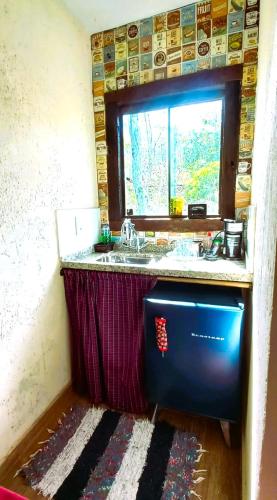 a kitchen with a sink and a window in a room at Pousada Contos da Lua Vaga in Milho Verde