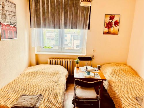 a room with two beds and a table and a window at ANELL Hostel in Poznań