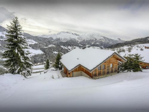 une cabane en rondins dans la neige avec des montagnes en arrière-plan dans l'établissement Chalet Parakima - OVO Network, à Manigod