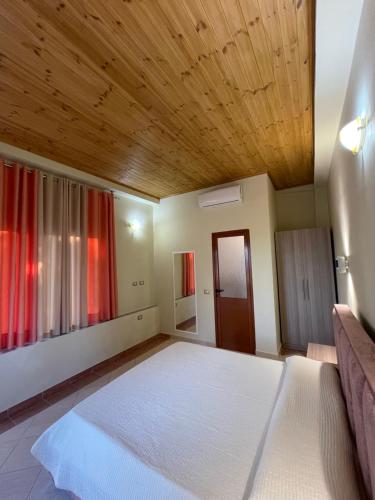 a bedroom with a large bed with a wooden ceiling at Harmonia Guest House in Vlorë