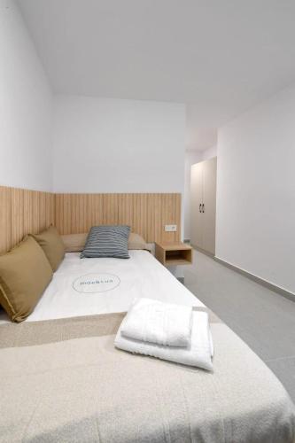 a large white bed with two white towels on it at Moebius - Habitaciones privadas con baño in León