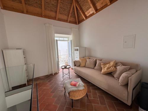 a living room with a couch and a table at Stylish townhouse with gallery in the heart of Tavira for two in Tavira