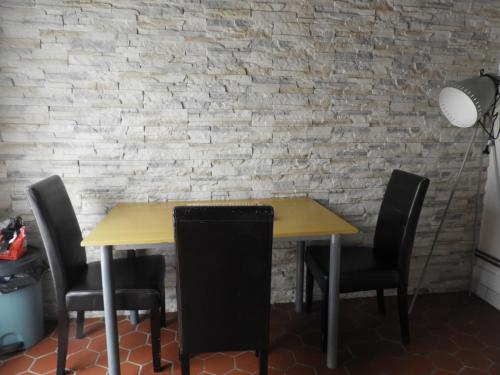une table à manger avec des chaises et un mur en briques dans l'établissement le chalet de la vallée, à Bouquelon