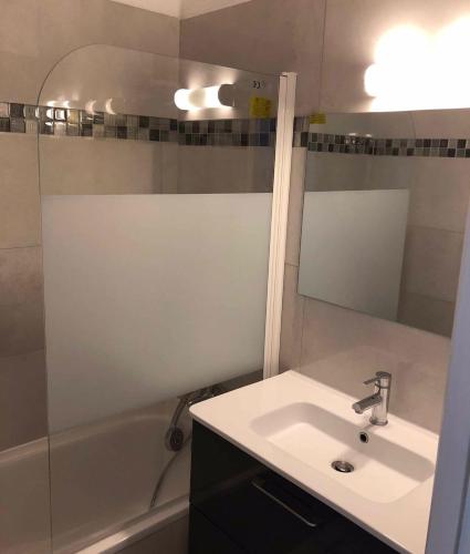 une salle de bain avec un lavabo, une baignoire et un miroir dans l'établissement Appartement Moriani plage, à San-Nicolao