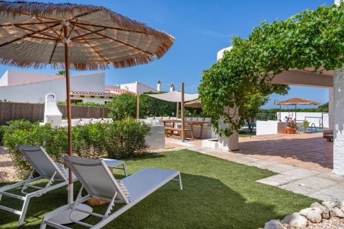 un patio con due sedie e un ombrellone di Villa Bini Ezolea a Binibeca