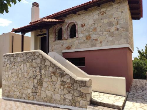 a house with a stone wall next to a building at Villa Panorama in Mola Kalyva