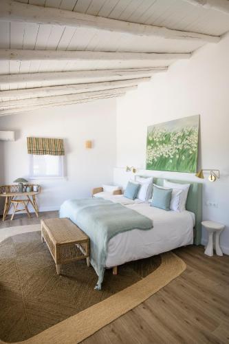 a white bedroom with a large bed and a table at Cortijo Genesis in Gaucín