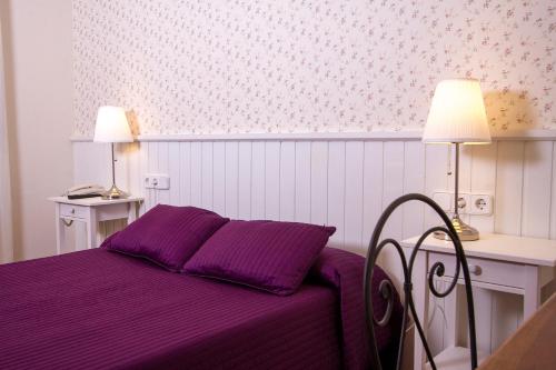 a bedroom with a purple bed with two lamps at Hotel Antiga in Calafell