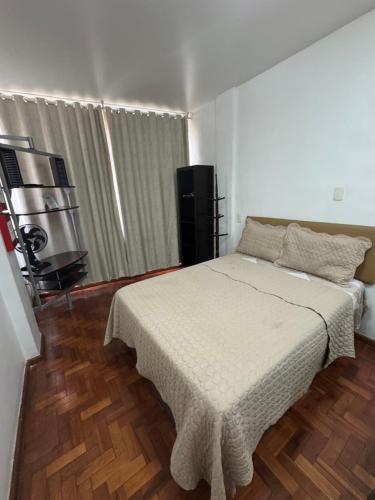 a bedroom with a white bed and a wooden floor at STUDIO IPANEMA CONFORTÁVEL in Rio de Janeiro